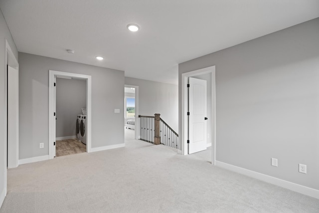 unfurnished bedroom featuring a spacious closet, baseboards, washing machine and dryer, light carpet, and recessed lighting