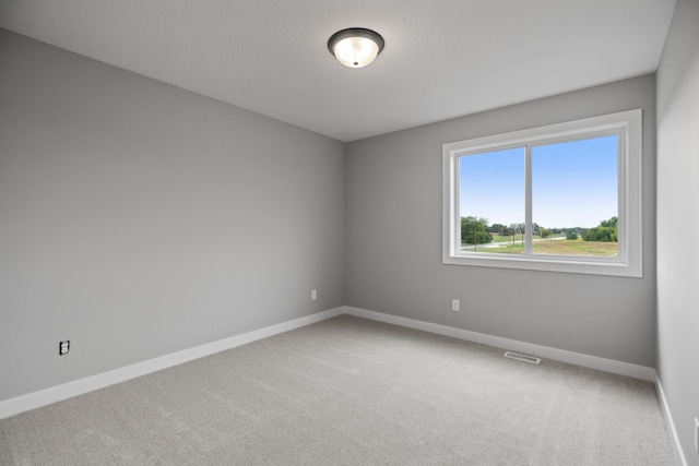 carpeted spare room featuring visible vents, a textured ceiling, and baseboards