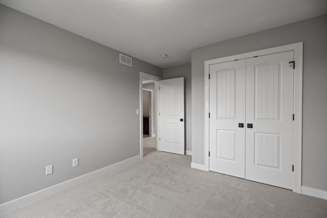 unfurnished bedroom featuring carpet, baseboards, visible vents, and a closet