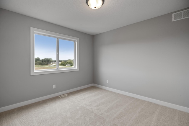 empty room featuring visible vents, baseboards, and light colored carpet