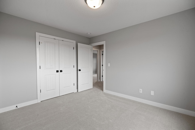 unfurnished bedroom with a closet, baseboards, carpet, and a textured ceiling