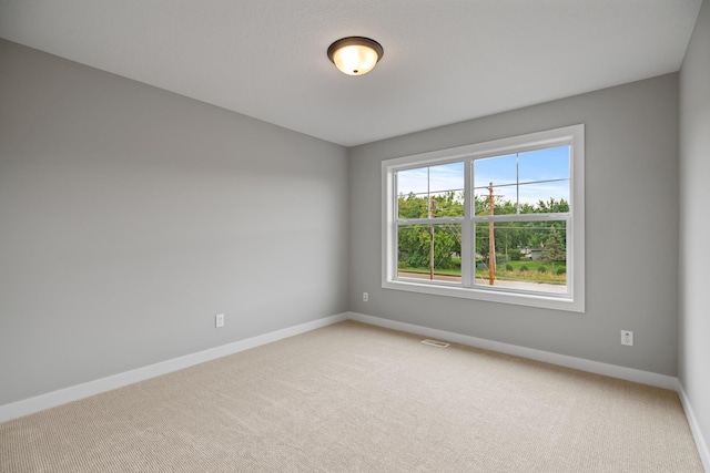 empty room with light carpet, visible vents, and baseboards