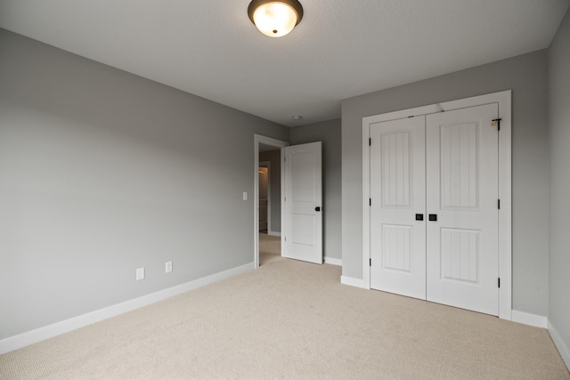 unfurnished bedroom with light colored carpet, baseboards, and a closet