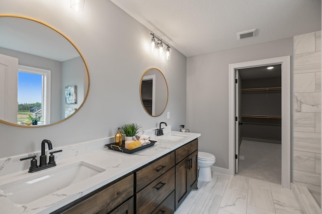 full bathroom with a textured ceiling, toilet, visible vents, and a sink