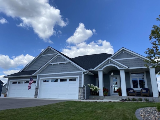 9551 230th St E, Lakeville, MN 55044 - craftsman-style house with covered porch, an attached garage, a front yard, stone siding, and concrete driveway