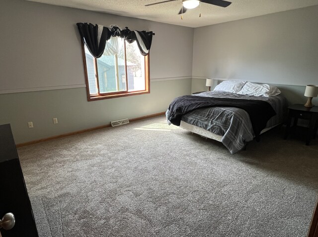 carpeted bedroom featuring baseboards, a ceiling fan, and visible vents