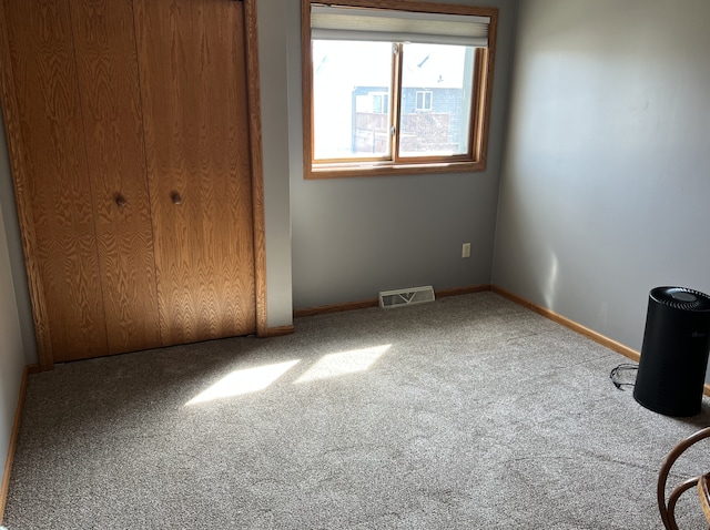 unfurnished bedroom featuring a closet, visible vents, baseboards, and carpet floors