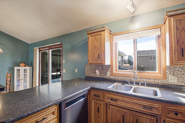 kitchen with decorative backsplash, dark countertops, dishwashing machine, and a sink