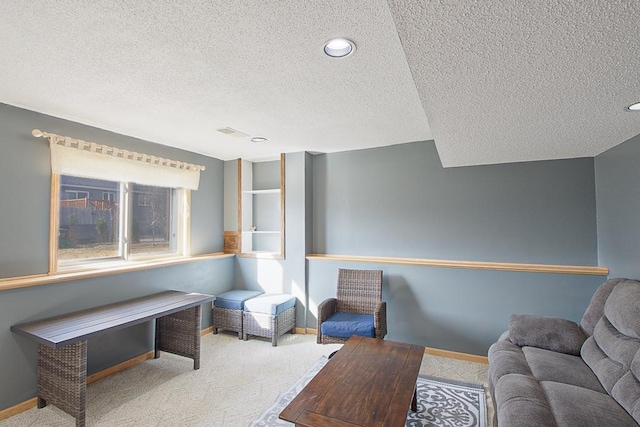 living area featuring carpet floors, baseboards, and a textured ceiling