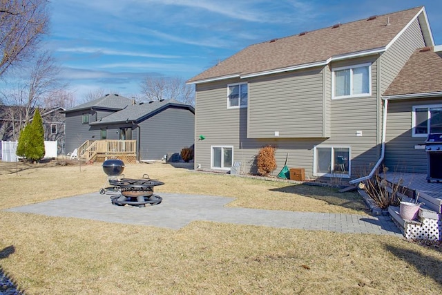 back of house with a patio area, a shingled roof, a wooden deck, and a yard