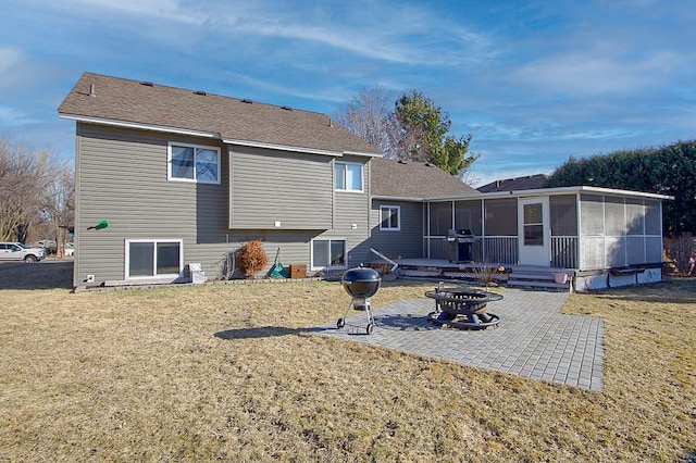 back of house featuring an outdoor fire pit, a sunroom, a yard, and a patio
