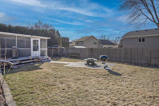 view of yard featuring a fire pit, a sunroom, a patio, and a fenced backyard