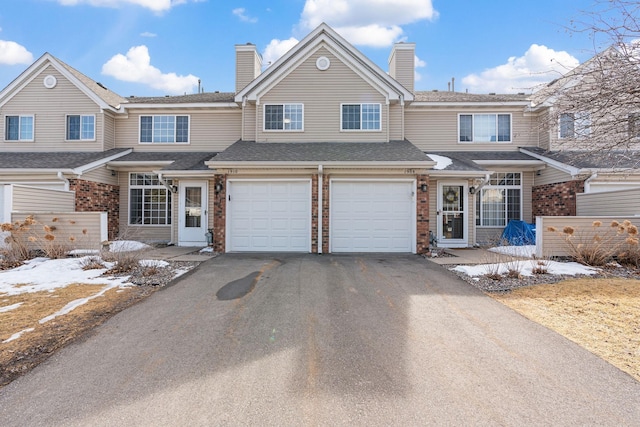 townhome / multi-family property with aphalt driveway, brick siding, and a chimney