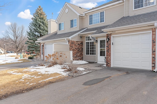 view of front of property with brick siding, a shingled roof, aphalt driveway, and a garage