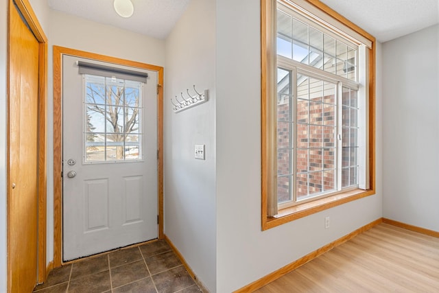 doorway with baseboards, a textured ceiling, and dark wood finished floors