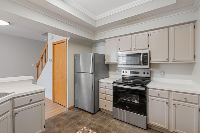 kitchen featuring a textured ceiling, stainless steel appliances, light countertops, and ornamental molding