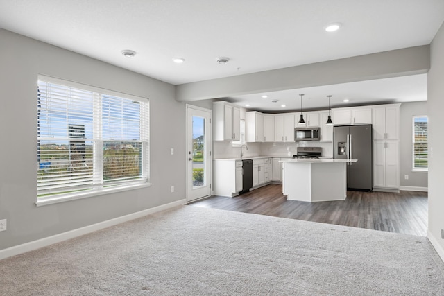 kitchen with carpet, baseboards, stainless steel appliances, light countertops, and open floor plan