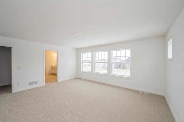 spare room with visible vents, light colored carpet, and baseboards