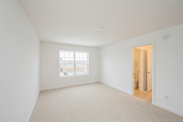 empty room featuring visible vents, baseboards, and light carpet