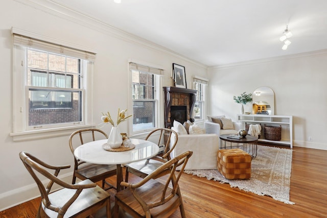 dining room with baseboards, wood finished floors, plenty of natural light, and a glass covered fireplace