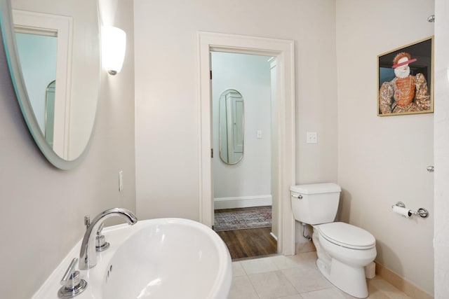 bathroom featuring tile patterned flooring, toilet, baseboards, and a sink