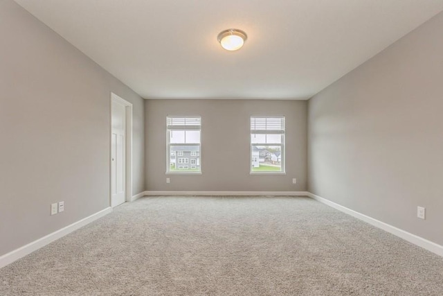 unfurnished room with light colored carpet and baseboards