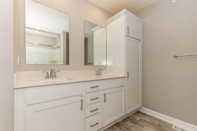 bathroom with a sink, baseboards, wood finished floors, and double vanity