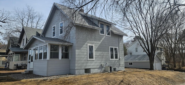 back of house featuring central AC unit, a sunroom, and a chimney