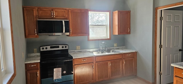 kitchen featuring stainless steel microwave, electric stove, brown cabinets, and a sink