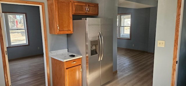 kitchen with light countertops, stainless steel fridge, light wood finished floors, and brown cabinets