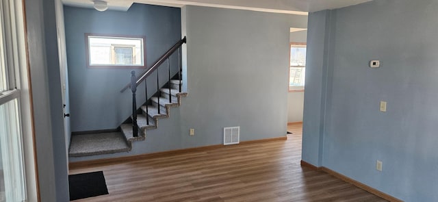 entryway featuring wood finished floors, stairway, a healthy amount of sunlight, and visible vents