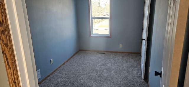 carpeted spare room featuring visible vents and baseboards