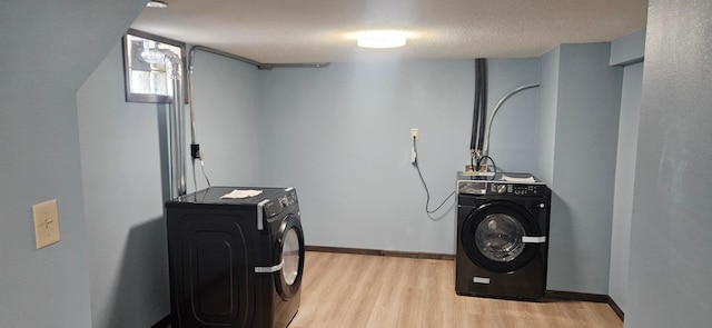 washroom featuring baseboards, washing machine and dryer, laundry area, light wood-style flooring, and a textured ceiling