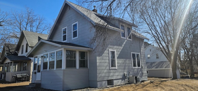 view of side of home with a chimney, central AC, and a sunroom