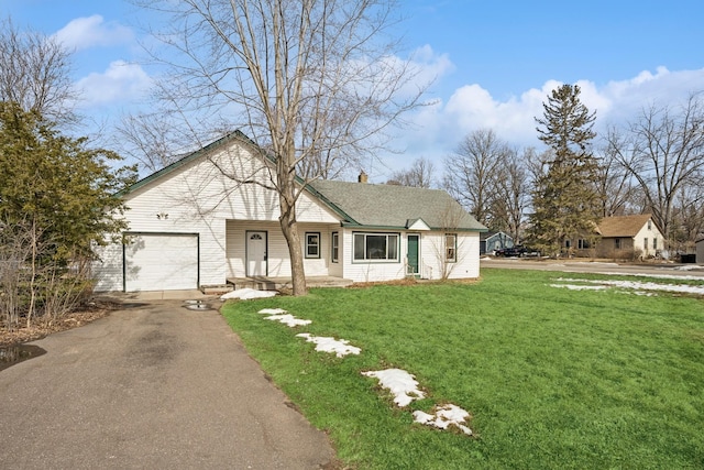 view of front facade with a front yard, covered porch, a chimney, and aphalt driveway