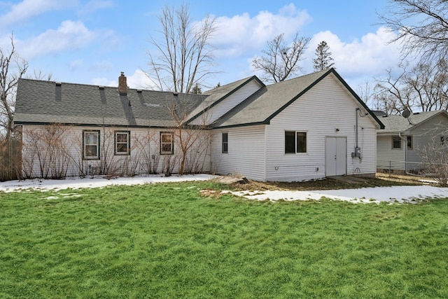 back of house with a shingled roof, a yard, and a chimney