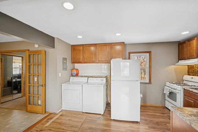 kitchen featuring under cabinet range hood, white appliances, light wood-style floors, and washing machine and clothes dryer