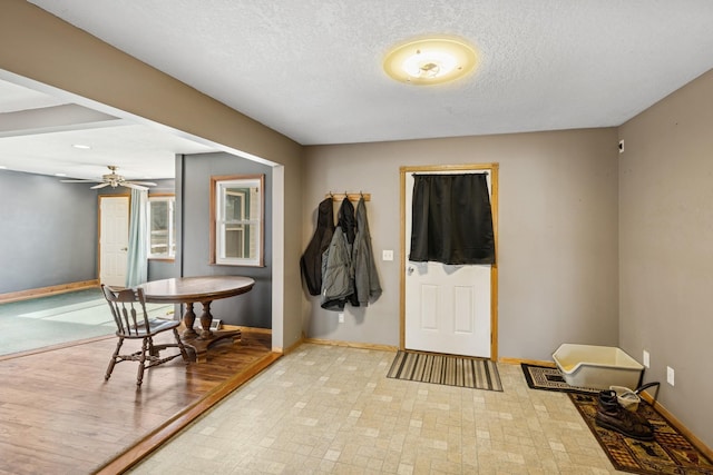 entryway with baseboards, a textured ceiling, and ceiling fan