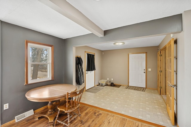 dining area with visible vents, beam ceiling, baseboards, and light wood-style flooring