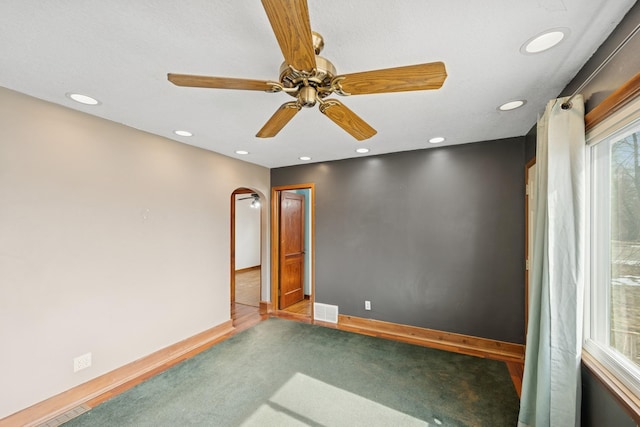 carpeted spare room featuring arched walkways, visible vents, recessed lighting, and baseboards