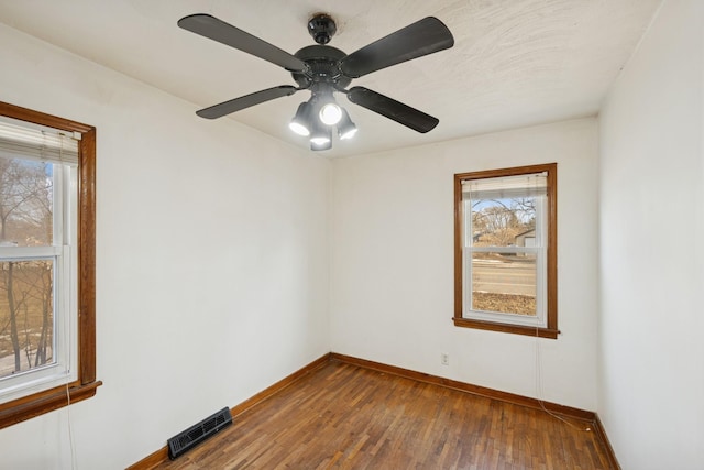 unfurnished room with visible vents, a ceiling fan, baseboards, and wood finished floors