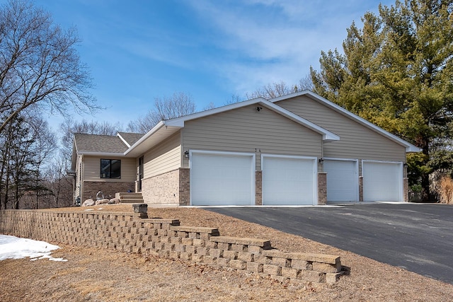 view of front of home with aphalt driveway, an attached garage, and brick siding