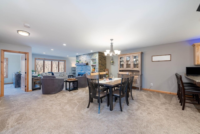 dining room featuring light carpet, recessed lighting, a fireplace, baseboards, and a chandelier