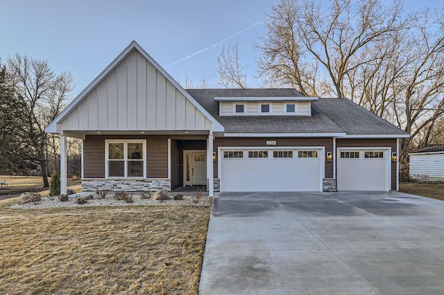 view of front facade with driveway, an attached garage, a shingled roof, stone siding, and board and batten siding