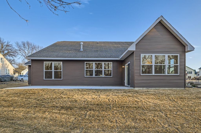 rear view of property featuring a patio, a lawn, and roof with shingles