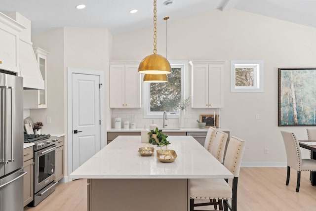 kitchen featuring backsplash, vaulted ceiling with beams, high quality appliances, light wood-type flooring, and a kitchen breakfast bar