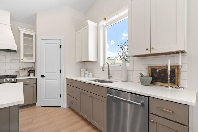 kitchen featuring stainless steel dishwasher, custom exhaust hood, gray cabinetry, and a sink