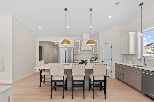 kitchen featuring a sink, a kitchen bar, glass insert cabinets, and appliances with stainless steel finishes