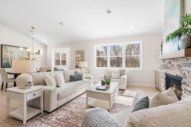 living room with plenty of natural light, light wood-style floors, a fireplace, and vaulted ceiling