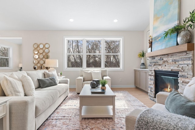 living area featuring recessed lighting, baseboards, a stone fireplace, and light wood finished floors